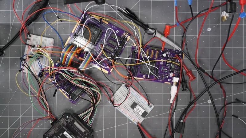 Three purple OshPark boards and a white bread board all attached using a number of jumper wires on a grey cutting mat.